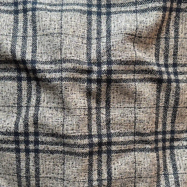 Närbild på Coco möbeltyg med rutmönster i beige och mörka toner, som visar den levande vävda strukturen och den mjuka men slitstarka ytan.