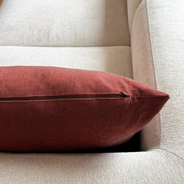 Närbild av tegelrött kuddfodral i mjukt tyg med linnekänsla