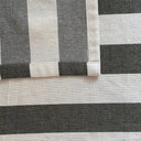 Närbild på fållen på en randig bordsduk i bomull som visar tygets struktur och sydda kant.