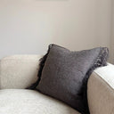 Kuddfodral Freja i strukturerat tyg med fransar, placerad på ljus soffa