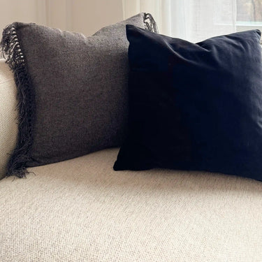 Freja kuddfodral tillsammans med mörk sammetskudde i soffmiljö