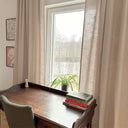 Beige gardiner som hänger längs fönster och ramar in rummet med mjuk textil känsla