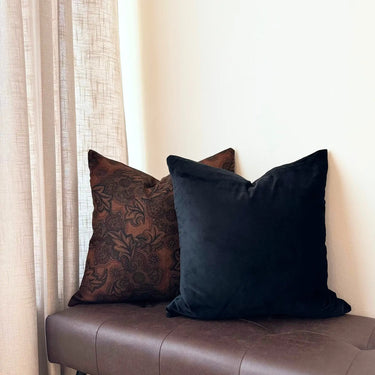 Svart prydnadskudde i sammet i stilren miljö med gardiner och andra kuddar