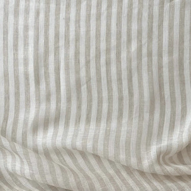 Randigt linnetyg Lotta i 100 % linne med diskreta vertikala ränder i beige och naturvitt, fotograferat plant för att visa väv och struktur.