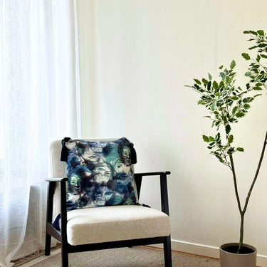 Prydnadskudde Lucy med abstrakt mönster i blå och gröna toner placerad på stol i ljus och modern inredning