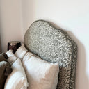 Detaljbild av sänggavel klädd i Masra tyg som visar struktur, mönster och kantavslut. Slitstarkt tyg i blandning av polyester, bomull, viskos och lin.