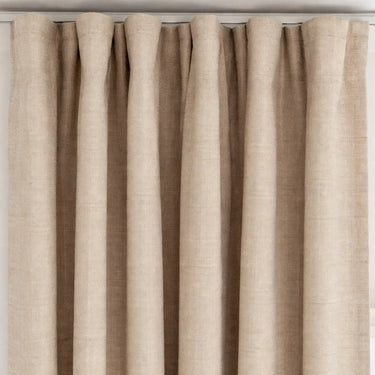 Beige gardin med jämna veck upptill, ger ett stilrent och mjukt fall