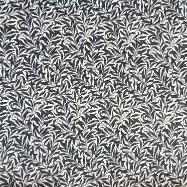 Mönstrat tyg Ramas i mörkgrå nyans, med tät väv och dekorativt bladmotiv.