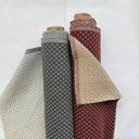 Möbeltyget Romeo i röd och grå färger med små geometriska motiv. Dubbelvävt tyg som kombinerar 50 % bomull och 50 % polyester för hållbar möbelomklädsel.