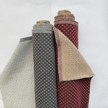 Möbeltyget Romeo i röd och grå färger med små geometriska motiv. Dubbelvävt tyg som kombinerar 50 % bomull och 50 % polyester för hållbar möbelomklädsel.