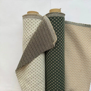 Dubbelvävt möbeltyg Romeo i naturtoner med små geometriska mönster. Tyget visas på rulle och uppvikt för att visa struktur och väv. Slitstarkt tyg i bomull och polyester.