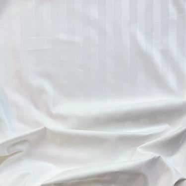 Satinvävd bomull i vit nyans med slät yta och mjuk glans, fotograferad i veck för att visa fall och struktur