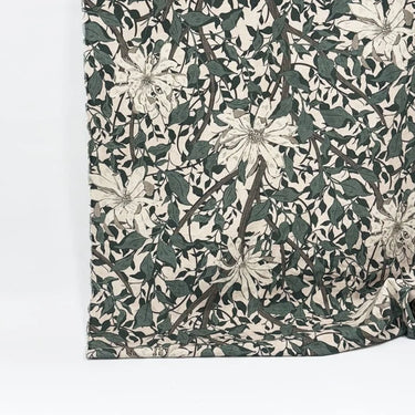 Mönstrat bomullstyg Siv med blommor och slingrande blad i gröna och beige toner, fotograferat med måttband för att visa mönsterskala