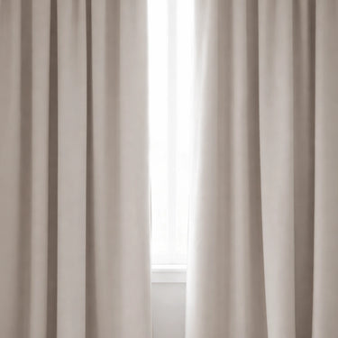 Mörkläggningsgardin i beige tyg som blockerar ljus framför fönster