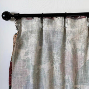 Detalj av gardin i linne med mjukt fall och veck, upphängd på gardinstång