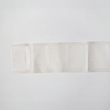 Veckband för gardiner fotograferat mot vit bakgrund. Gardinband som sys fast på baksidan av gardinen för att skapa jämna, eleganta veck med fingerkrokar.