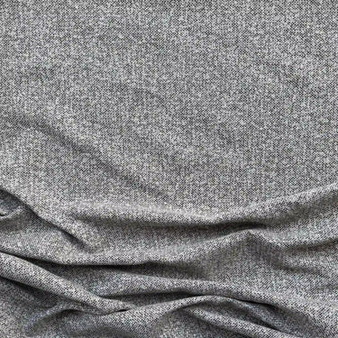 Närbild på möbeltyget Alex i 100 % polyester med diskret vävd struktur i beigegrå toner, visat med mjukt fall som framhäver tygets naturliga känsla och slitstyrka.