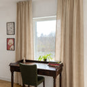 Beige gardiner i linnelook upphängda i vardagsrum med skrivbord och stol, mjukt ljusinsläpp