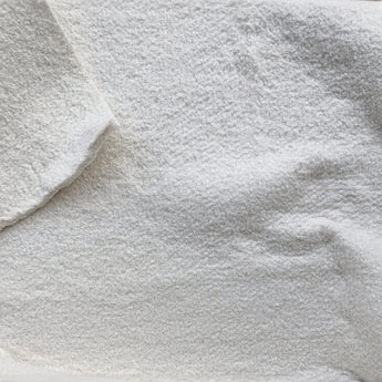 Närbild av vit bomullsvadd som metervara. Mjukt, följsamt och delbart mellanlägg i bomull, perfekt för quiltning, lapptäcken, sängkläder och andra vadderade sömnadsprojekt.