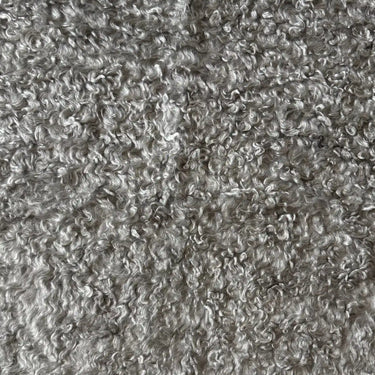 Närbild av Dolly möbeltyg i 100 % polyester med mjuk, strukturerad yta i ljusgrå nyans.