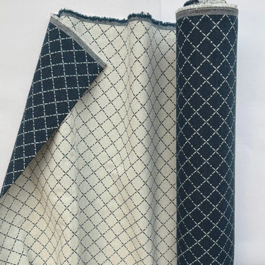 Närbild på möbeltyget Ester där tyget är uppvikt för att visa vävstruktur och baksida. Rutigt dubbelvävt tyg i 50 % bomull och 50 % polyester som passar för möbelklädsel.