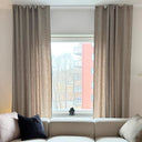 Beige gardinlängder i linnelook monterade vid fönster i vardagsrum, visar gardinens fall och längd