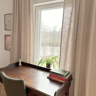 Beige gardiner som hänger längs fönster och ramar in rummet med mjuk textil känsla