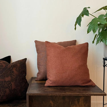 Brun-orange prydnadskudde Greenwich i stilren miljö med växt och träbord