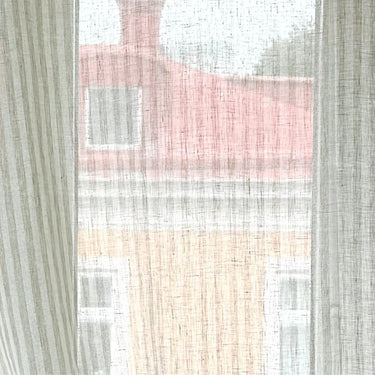 Skirt linnetyg Lotta i 100 % linne, upphängt framför fönster för att visa transparens, struktur och naturligt ljusgenomsläpp.