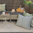 Grönrandigt utevävstyg använt till utomhuskuddar på uteplats med möbler och dekor.