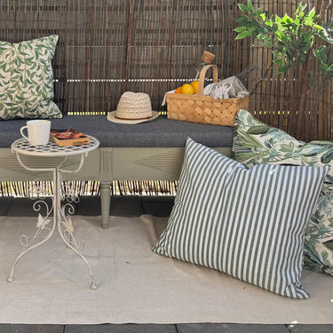 Grönrandigt utevävstyg använt till utomhuskuddar på uteplats med möbler och dekor.