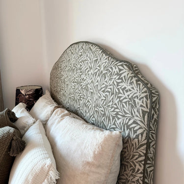 Detaljbild av sänggavel klädd i Masra tyg som visar struktur, mönster och kantavslut. Slitstarkt tyg i blandning av polyester, bomull, viskos och lin.