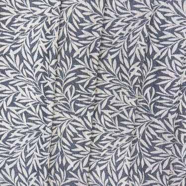 Masra möbeltyg i mörk blågrå nyans med dekorativt växtmönster. Bilden visar tygets struktur och hur mönstret framträder i veck.