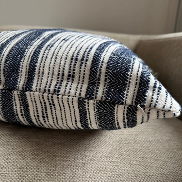 Närbild av kuddfodral i bomull med tydlig vävd struktur och mörkblå mönsterdetaljer