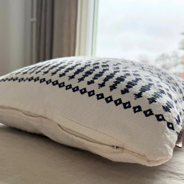 Närbild av kuddfodral i bomull och linne med struktur och mörkblå/grå mönsterdetaljer
