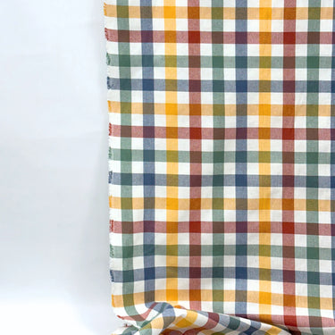 Rutigt tyg i grönt, gult, blått och vinrött hänger mot ljus bakgrund. Tyg i 80 % återvunnen bomull och 20 % återvunnen polyester med mjuk känsla och klassisk design.