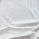 Satinvävd bomull i vit nyans med slät yta och mjuk glans, fotograferad i veck för att visa fall och struktur