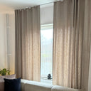 Närbild på beige gardintyg med linneliknande struktur och naturligt ljus som passerar genom tyget