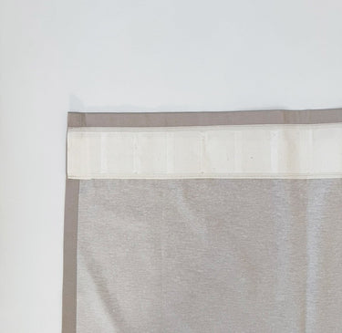 Närbild av veckband som är fastsytt på gardinens baksida. Visar hur bandet placeras upptill för att skapa ett stilrent och skräddarsytt fall.