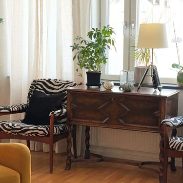 Fåtöljer klädda i möbeltyget Wilda med djärvt zebramönster i svart och beige, kombinerat med mjuk sammetskänsla som ger rummet karaktär och visuell kraft.