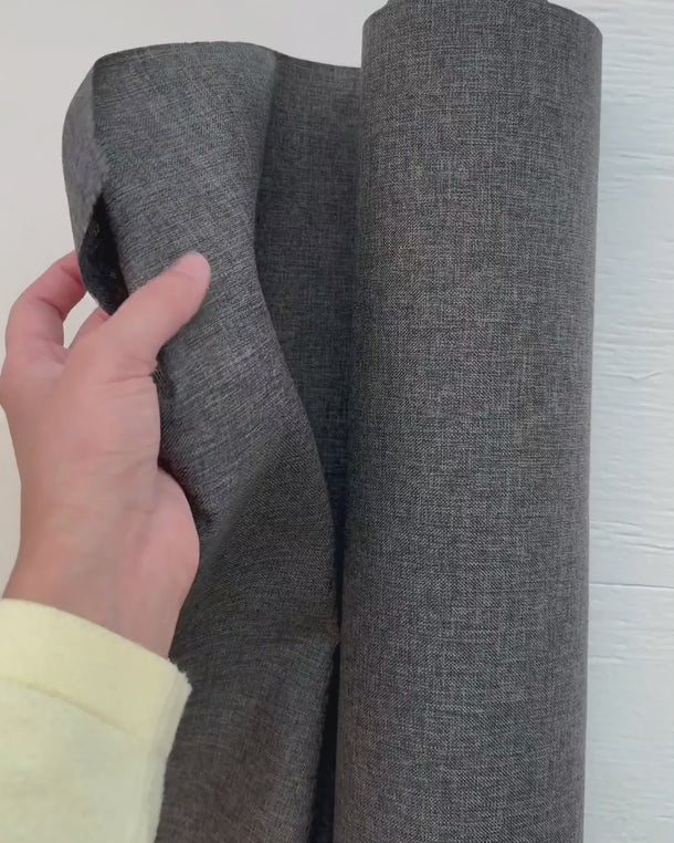 Hand som visar struktur och tjocklek på ljusbeständigt utomhustyg för dynor och utemöbler.