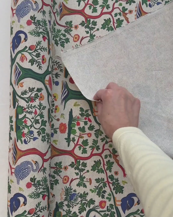 Hand som rör möbeltyget Alice och visar tygets egenskaper och naturliga struktur i rörelse.