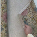 Hand som visar strukturen och baksidan på det mönstrade möbeltyget Anastasia med blommotiv.