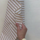 Hand som visar strukturen på den randiga uteväven Marina för dynor och utomhustextilier.