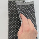 Video på mörkt möbeltyg Romeo med små geometriska mönster. Hand visar tygets struktur, väv och tjocklek – slitstarkt tyg för möbelomklädsel.