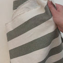 Hand som visar strukturen i det randiga tyget Filippa i grön och natur