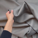 Hand som visar strukturen på mörkläggningstyget Svala i grå