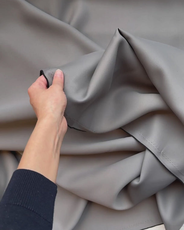 Hand som visar strukturen på mörkläggningstyget Svala i grå
